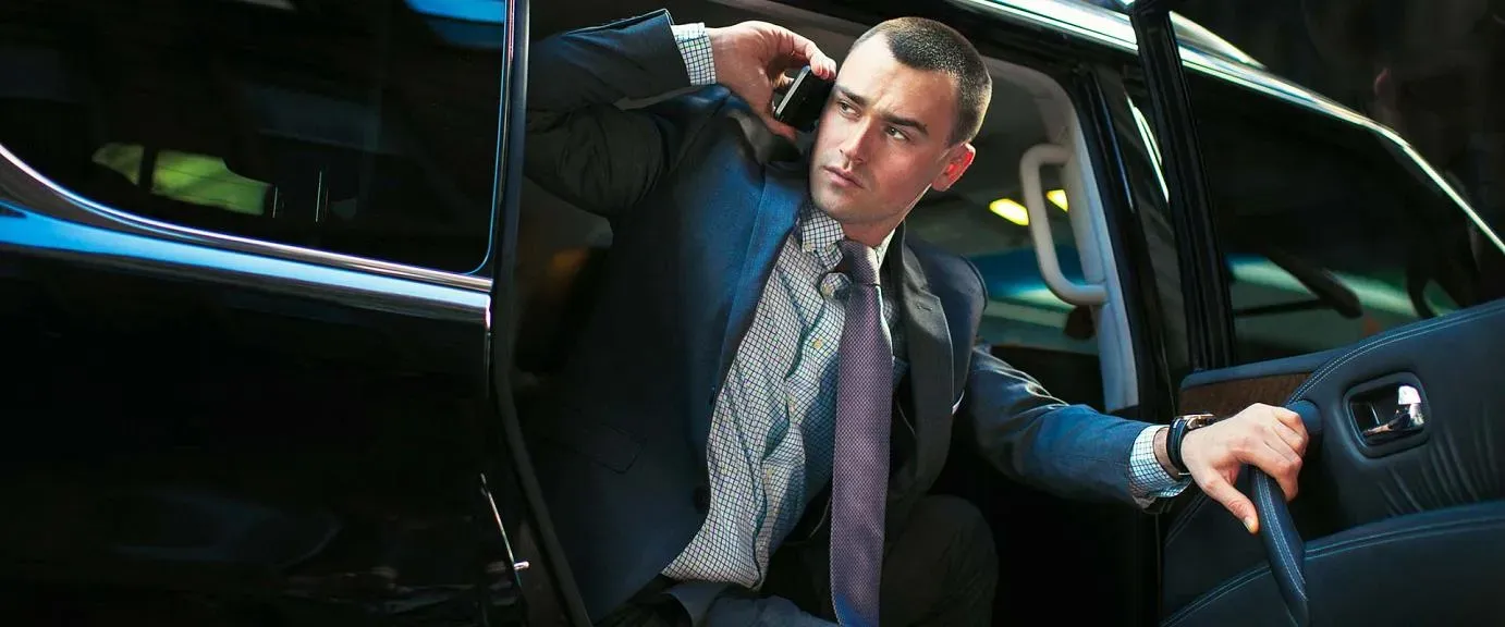 Chauffeur assisting a guest with luggage at a luxury hotel in Houston, showcasing executive car service